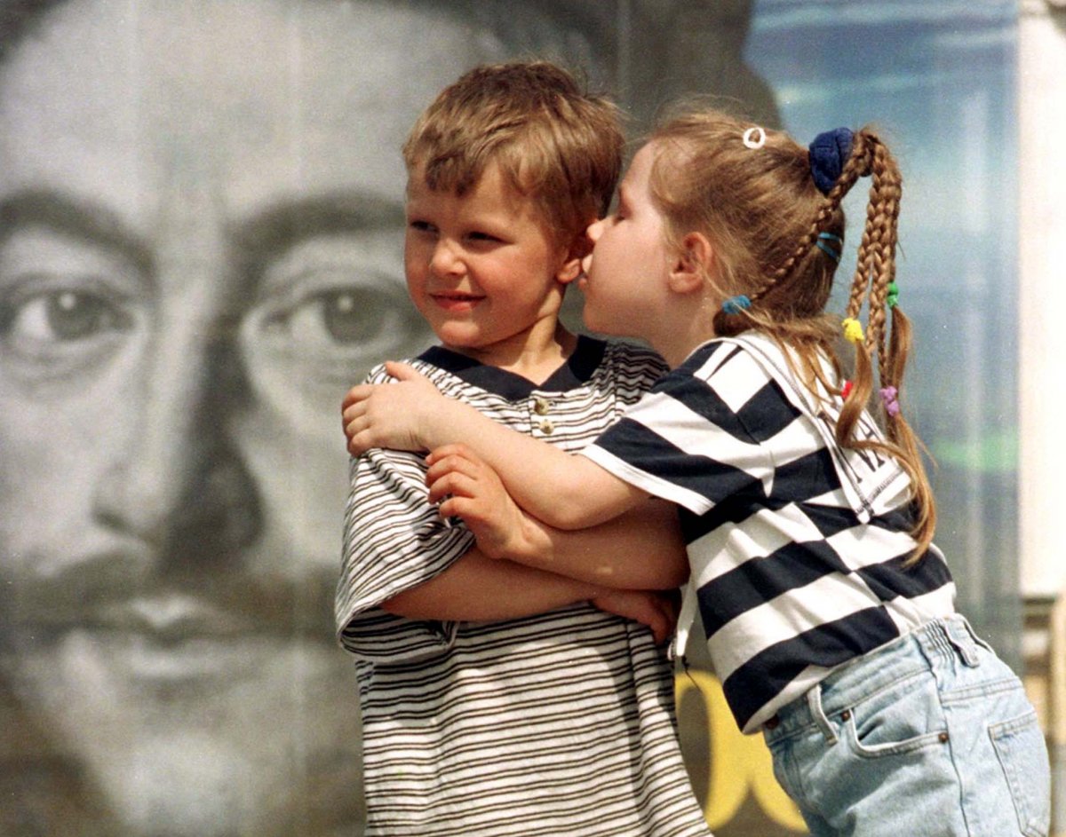 Reuters / Due bambini con alle spalle un poster di Pietro il Grande, 23 maggio 1999.